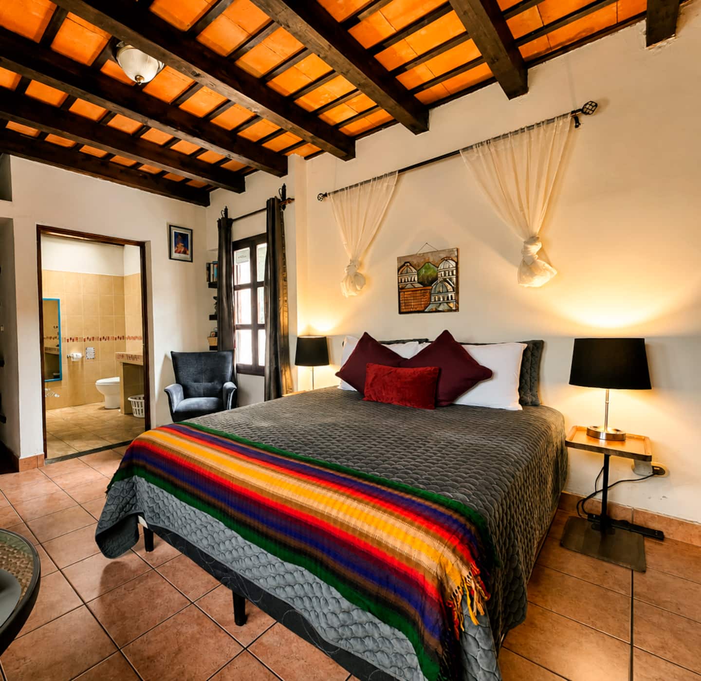 Condesa’s queen bed with woven Guatemalan textiles beneath a timber and tile ceiling